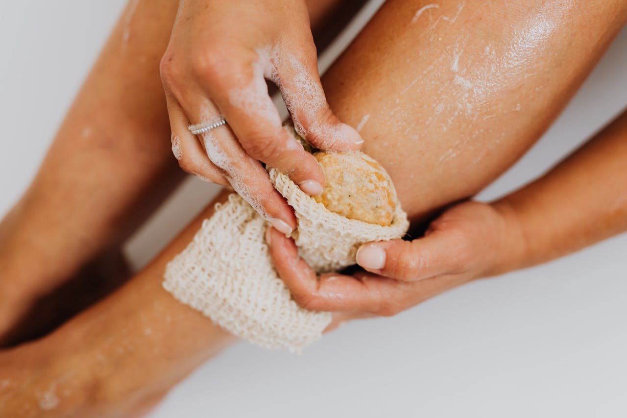 Mastering the First Impression: Your intriguing post title goes here Detailed view of a person exfoliating their leg with a natural loofah sponge for skin care.